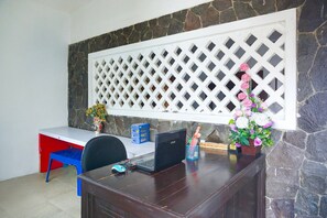 A desk with a laptop, a chair, a vase with flowers, and a decorative lattice panel.