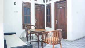 A room with a tiled floor, a round wooden table, two wooden chairs, and three wooden doors with shutters. - Luxury Deluxe DBL Retreat W/ Free WiFi and Parking (Bandar Lampung)
