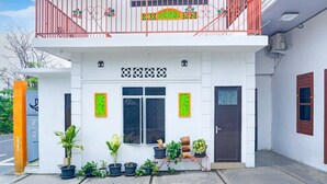 A two-story building with a balcony, potted plants, and a door with a sign. - Luxury Deluxe DBL Retreat W/ Free WiFi and Parking (Bandar Lampung)