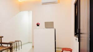 A room with a white wall, a ceiling with recessed lighting, a white air conditioning unit, a small table with a chair, and a red stool. - Luxury Deluxe DBL Retreat W/ Free WiFi and Parking (Bandar Lampung)