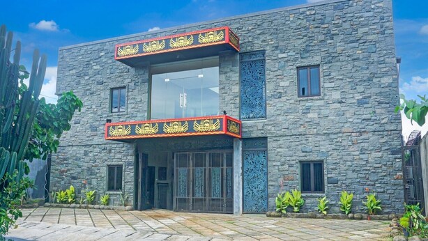 A modern building with a stone facade, a glass entrance, and a balcony with decorative railings. - Luxury Deluxe DBL Retreat W/ Free WiFi and Parking (Bandar Lampung)