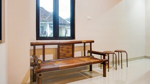 A room with a wooden bench, two stools, a window with a view of buildings, and a light switch on the wall. - Luxury Deluxe DBL Retreat W/ Free WiFi and Parking (Bandar Lampung)