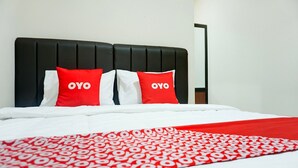 A bed with a black headboard, white bedding, and two red pillows with 'OYO' text. - Luxury Deluxe DBL Retreat W/ Free WiFi and Parking (Bandar Lampung)