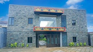 A modern building with a stone facade, a large entrance with a decorative arch, and a gated driveway. - Luxury Deluxe DBL Retreat W/ Free WiFi and Parking (Bandar Lampung)