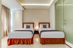 Une chambre d’hôtel avec deux lits, une table de chevet, une lampe, une porte coulissante et une fenêtre avec des rideaux.