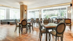 Tilava ravintola, jossa on puulattiat, useita pöytiä ja tuoleja sekä suuret ikkunat, joista avautuu näkymä ulos.