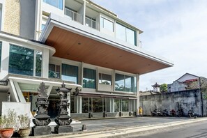 A modern two-story building with large windows, a covered entrance, and a parking area with motorcycles.