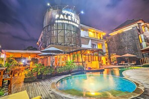 Een hotel met een zwembad, terras en een bord waarop 'PALETTE' staat.