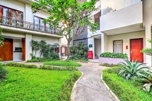 Een binnentuin met een pad in het midden, omgeven door groen en gebouwen met balkons.