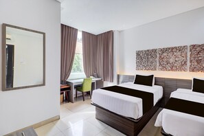 Een hotelkamer met twee bedden, een bureau, een stoel en een grote spiegel.