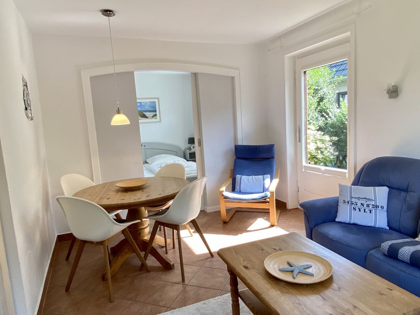 A cozy room with a dining table, chairs, a sofa, and a window with a view.