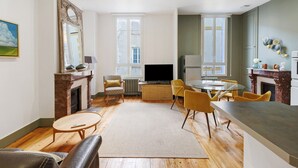 Un salon moderne avec une cheminée, un téléviseur et un coin repas doté de chaises jaunes.