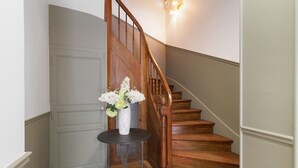 Un escalier en bois avec un vase de fleurs posé sur une petite table.
