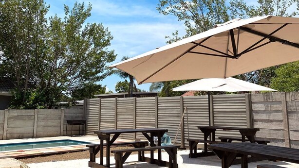 Eine Terrasse im Freien mit Picknicktischen und einem Schwimmbecken.