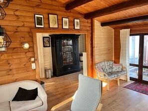 Puisesti sisustettu tila, jossa on takka, sohva, nojatuoli ja ruokapöytä.