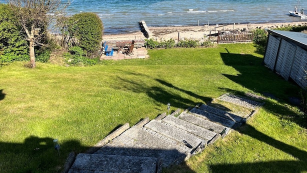 A grassy area with a stone pathway leading to a dock by the sea. - fewo1846 - Haus Utkiek - fewo1846 - Utkiek / Three-bedroom vacation home (Glücksburg (Ostsee))