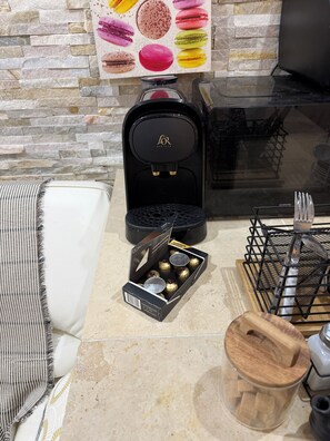 Une cuisine équipée d’une machine à café, d’une boîte de chocolats, d’un four à micro-ondes et d’une planche à découper en bois.