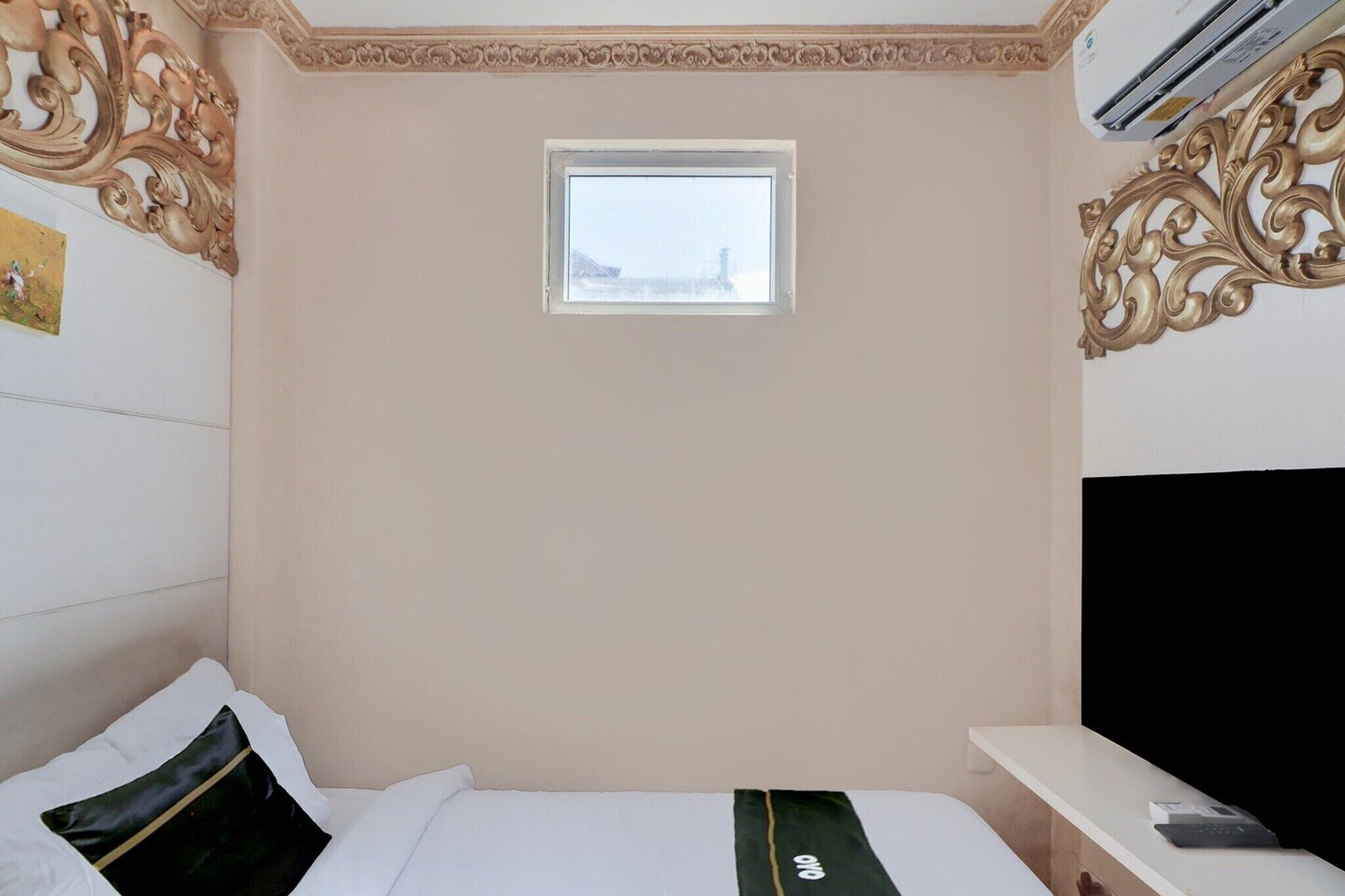 Ein Hotelzimmer mit Bett, kleinem Fenster, Klimaanlage und einer Wandverkleidung.