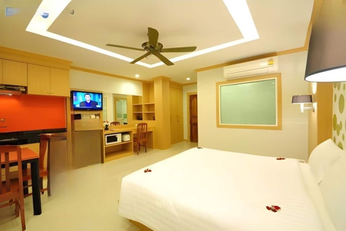 A hotel room with a bed, a desk, a television, and a ceiling fan.