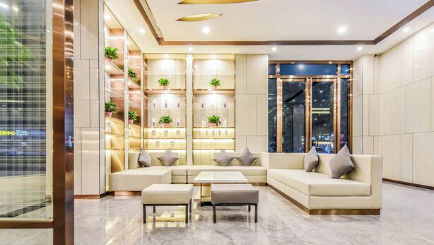 A modern lobby with a sectional sofa, a coffee table, and a shelving unit with plants. - Lavande Hotel Tianmenshan Branch (Zhangjiajie)