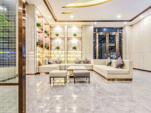 A modern lobby with a sectional sofa, a coffee table, and a shelving unit with plants. - Lavande Hotel Tianmenshan Branch (Zhangjiajie)
