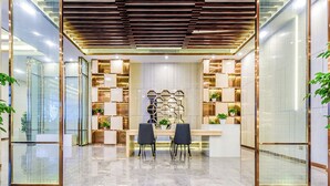 A modern interior with a marble floor, two black chairs, a wooden ceiling, and a wall with hexagonal shelves. - Lavande Hotel Tianmenshan Branch (Zhangjiajie)