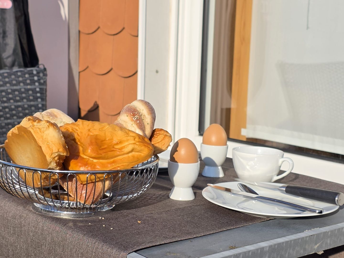 A breakfast setup with bread, eggs, and utensils on a table near a window.