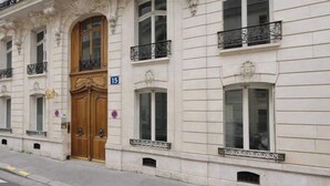 Un edificio con un'ampia porta in legno, diverse finestre e un balcone con ringhiere in ferro battuto.