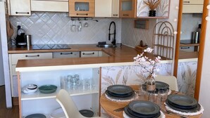 Una cocina compacta con comedor, que incluye una mesa redonda con platos, una cafetera y un lavamanos.