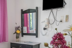 A bathroom with a mirror, a vanity, a flower vase, a television mounted on the wall, and a telephone. - Room 9 at Pagali Hotel with Queen Bed (Órmos Aiyialís)