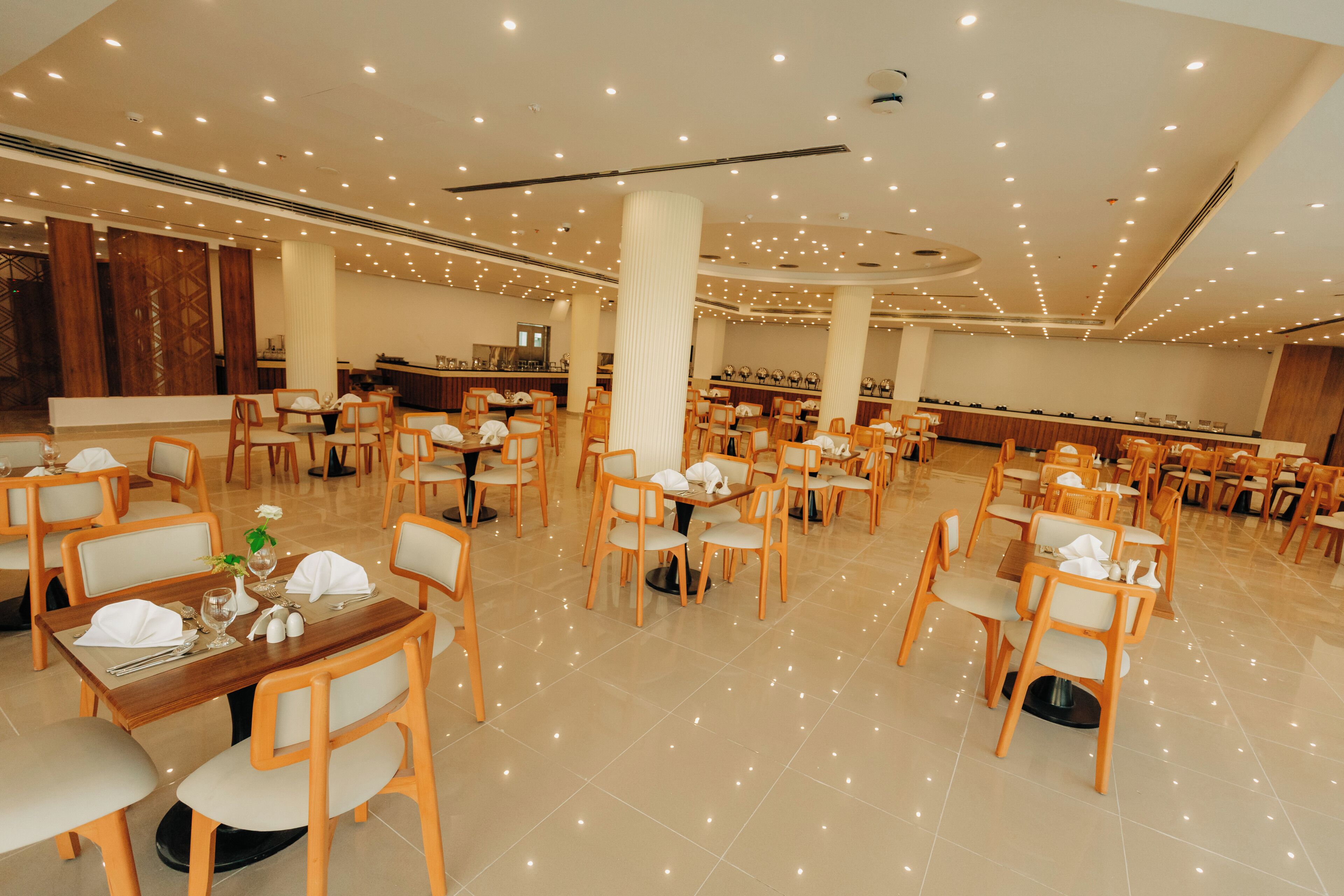 A spacious dining area with multiple tables and chairs, a central pillar, and a reception desk.