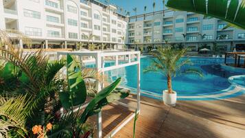 A hotel with a pool area, surrounded by tropical plants and palm trees.
