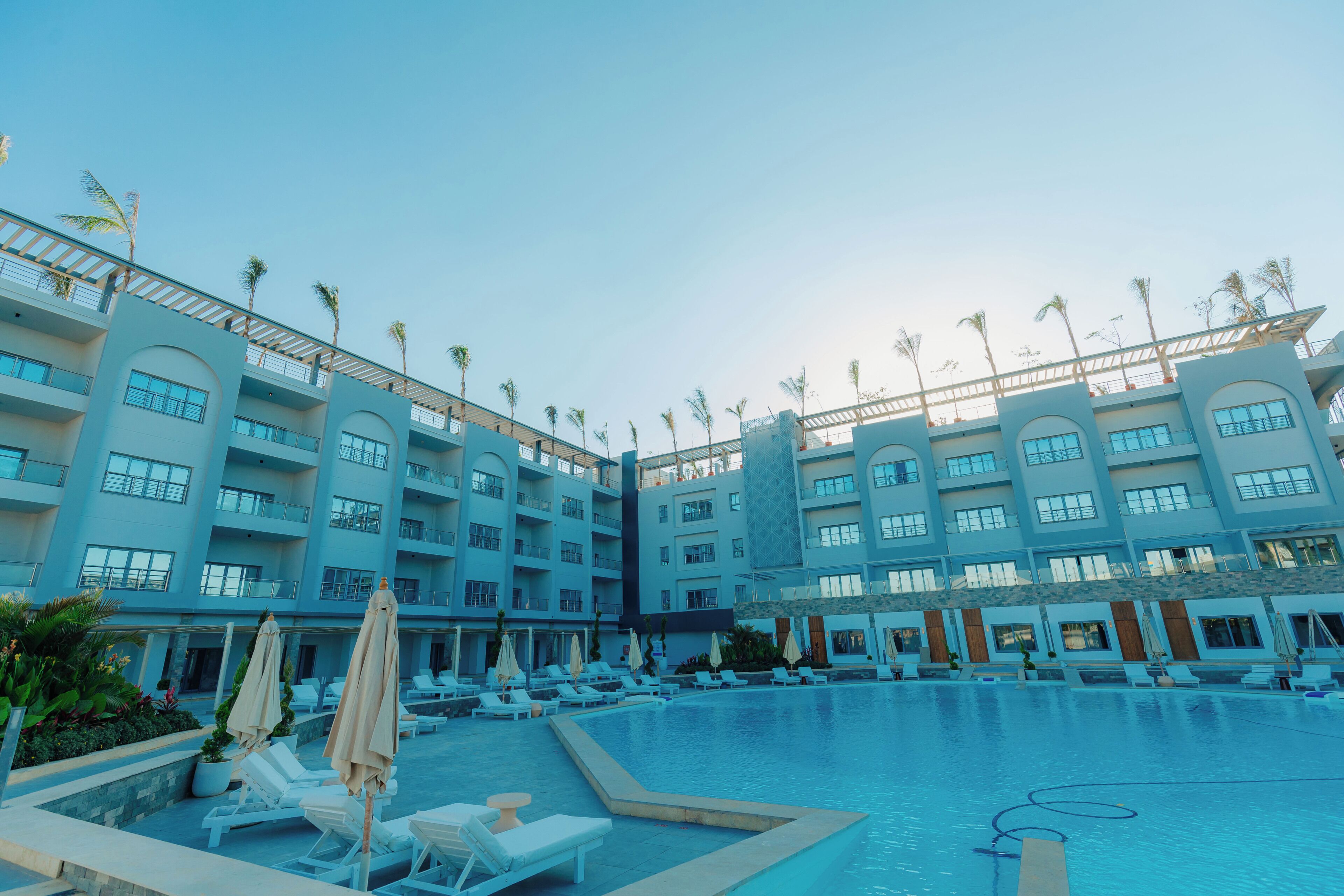 Hotel amb piscina, gandules i palmeres.