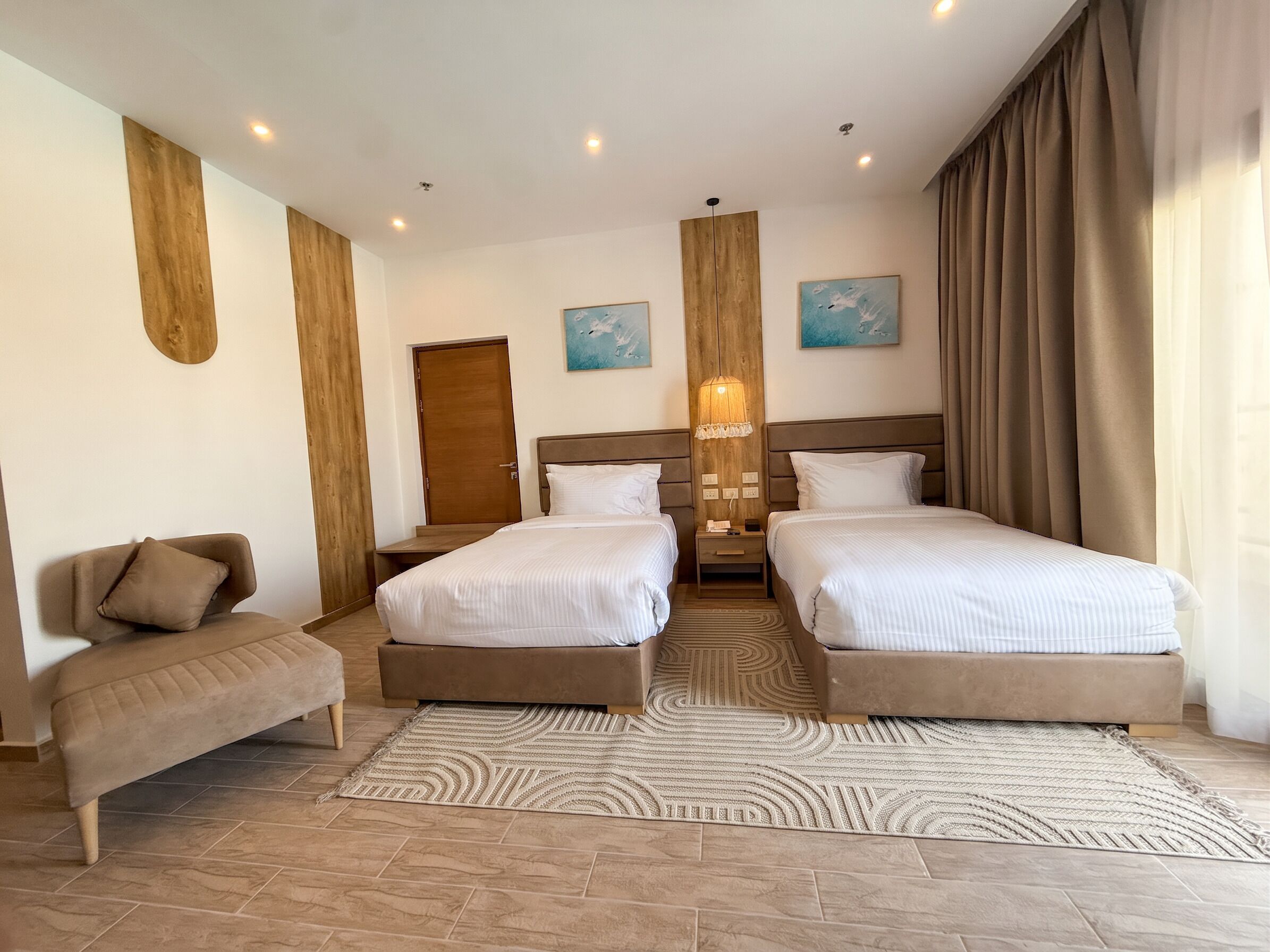 Une chambre d’hôtel avec deux lits, un canapé, un mur décoratif en bois et un tapis à motifs.