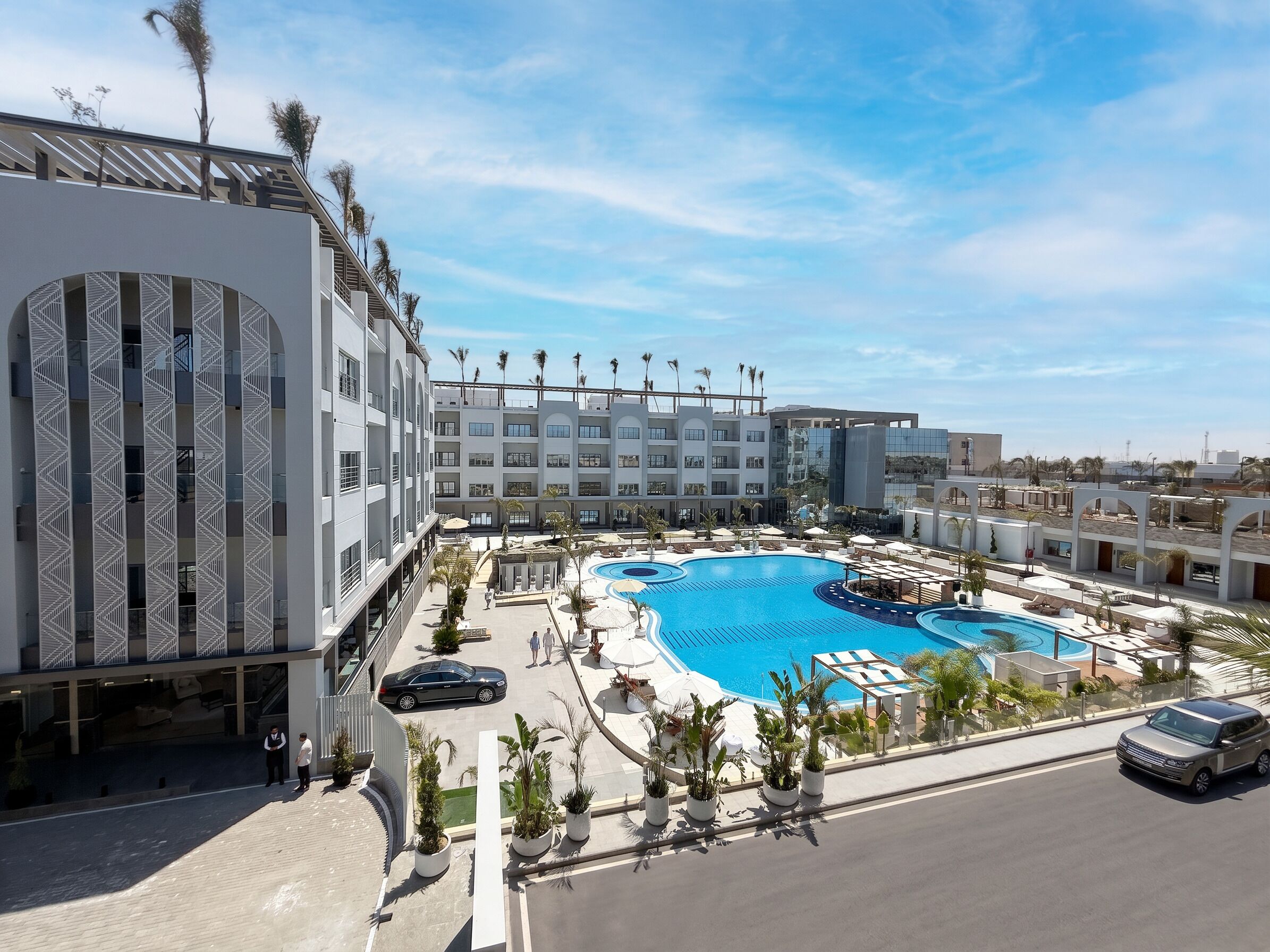 Ein Hotel mit großem Schwimmbad, mehreren Balkonen und modernem architektonischem Design.