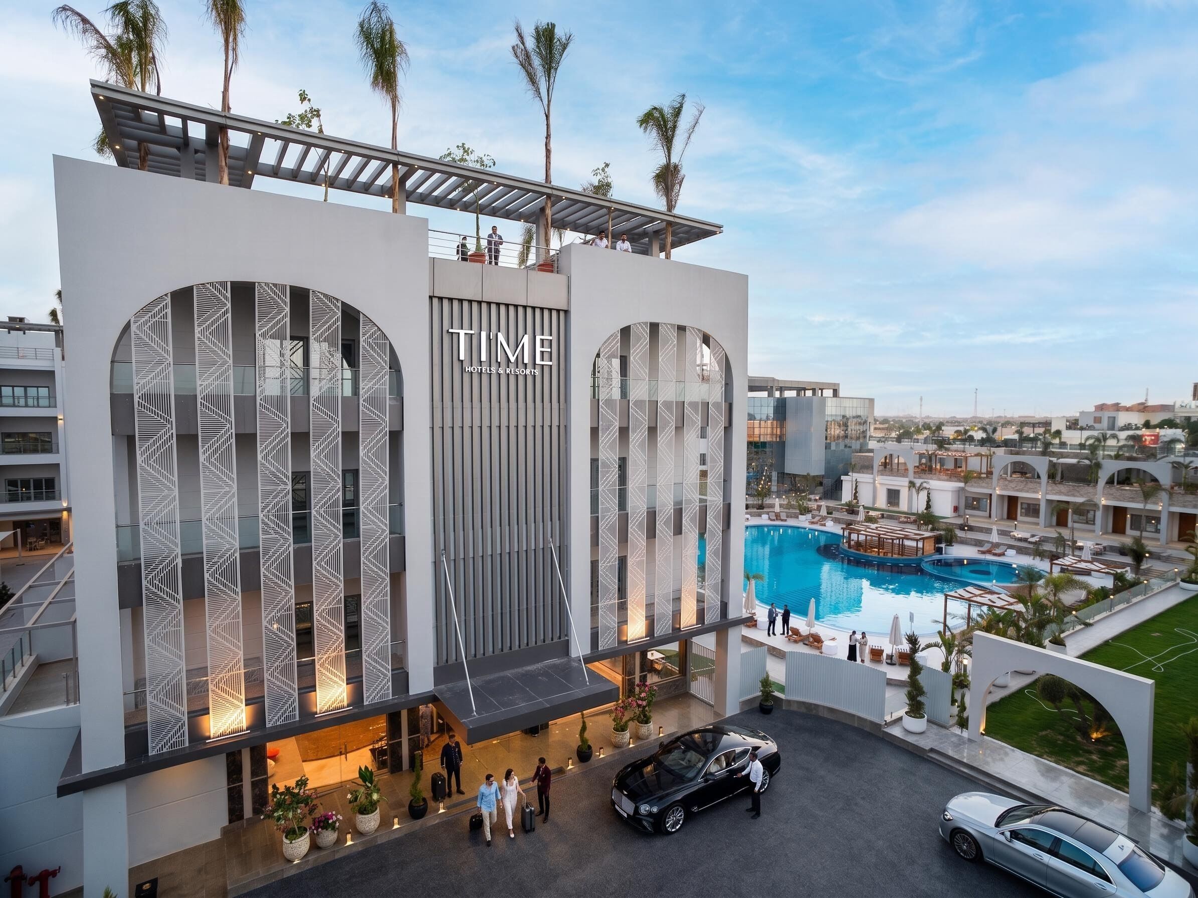 Un hotel moderno con una piscina grande, un área exterior cubierta y una terraza en la azotea.