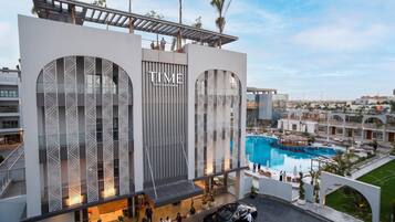 Un hotel moderno con una piscina grande, un área exterior cubierta y una terraza en la azotea.