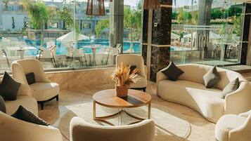Un espace de détente moderne avec vue sur la piscine, comprenant des canapés, une table basse et des luminaires suspendus.