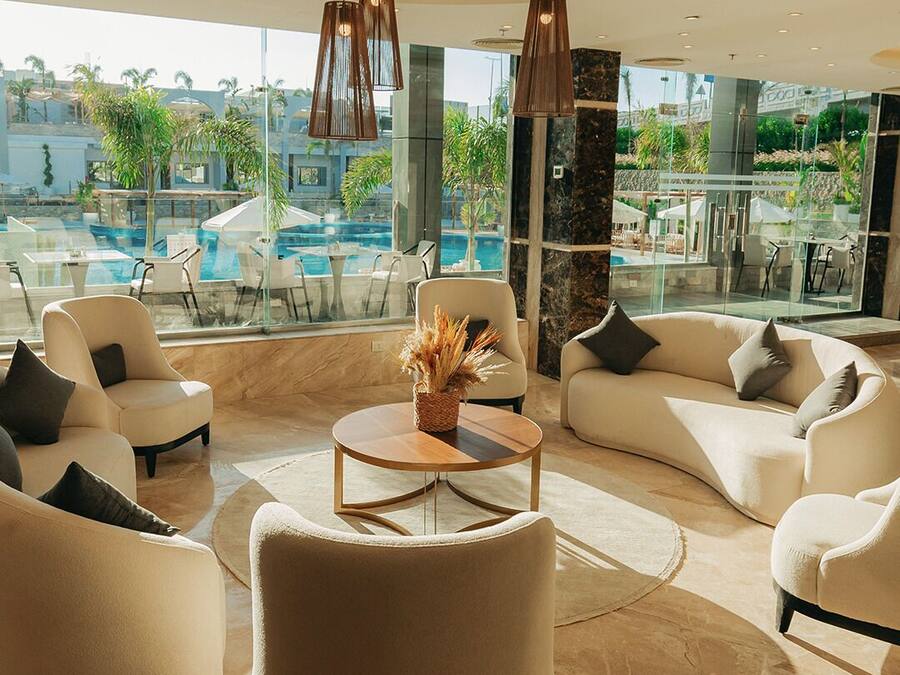 A modern lounge area with a pool view, featuring sofas, a coffee table, and pendant lighting.