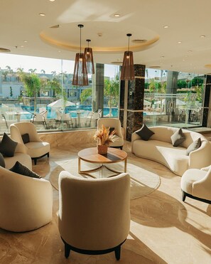 A modern lounge area with a pool view, featuring sofas, a coffee table, and pendant lighting. - TIME Marina North Coast  (Al-Hammam)