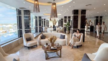 A spacious lobby with a pool view, modern furniture, and a central coffee table.