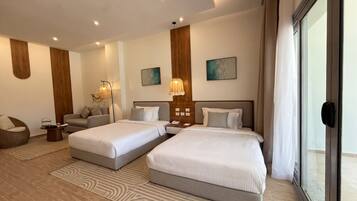 A hotel room with two beds, a sofa, a coffee table, and artwork on the walls.