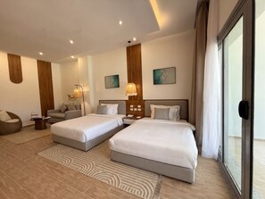 A hotel room with two beds, a sofa, a coffee table, and artwork on the walls. - TIME Marina North Coast  (Al-Hammam)