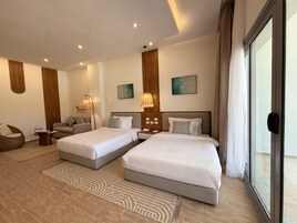 Habitación de hotel con dos camas, un sofá, una mesa de centro y obras de arte en las paredes.