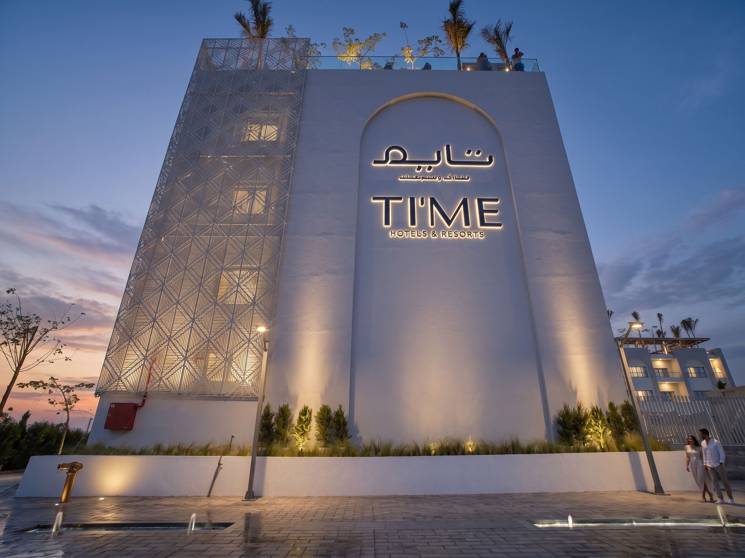 A modern hotel facade with a geometric pattern and a prominent sign for 'TIME Hotels & Resorts'.