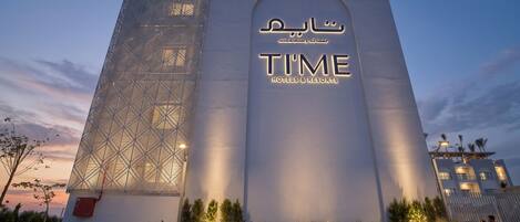 A modern hotel facade with a geometric pattern and a prominent sign for 'TIME Hotels & Resorts'.