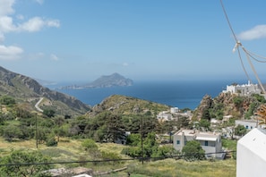 Un village côtier avec des bâtiments, une route sinueuse et une vue sur la mer et une île lointaine.