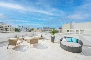 A rooftop terrace with outdoor seating, a potted plant, and a view of the cityscape. - Lovely 3BR Penthouse in Shenkin area by HolyGuest (Tel Aviv-Yafo)