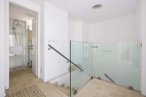 A modern bathroom with a glass shower enclosure, a white sink, and a glass door leading to a hallway. - Lovely 3BR Penthouse in Shenkin area by HolyGuest (Tel Aviv-Yafo)