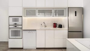 Une cuisine moderne avec des meubles blancs, un réfrigérateur en acier inoxydable, un four encastré et un lave-vaisselle.
